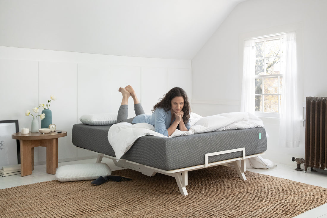 Woman laying on her stomach with legs bent up on top of a Tuft & Needle mattress and adjustable bed frame in a bedroom