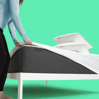 Person fitting a Tuft & Needle mattress protector over a Tuft & Needle Original II mattress