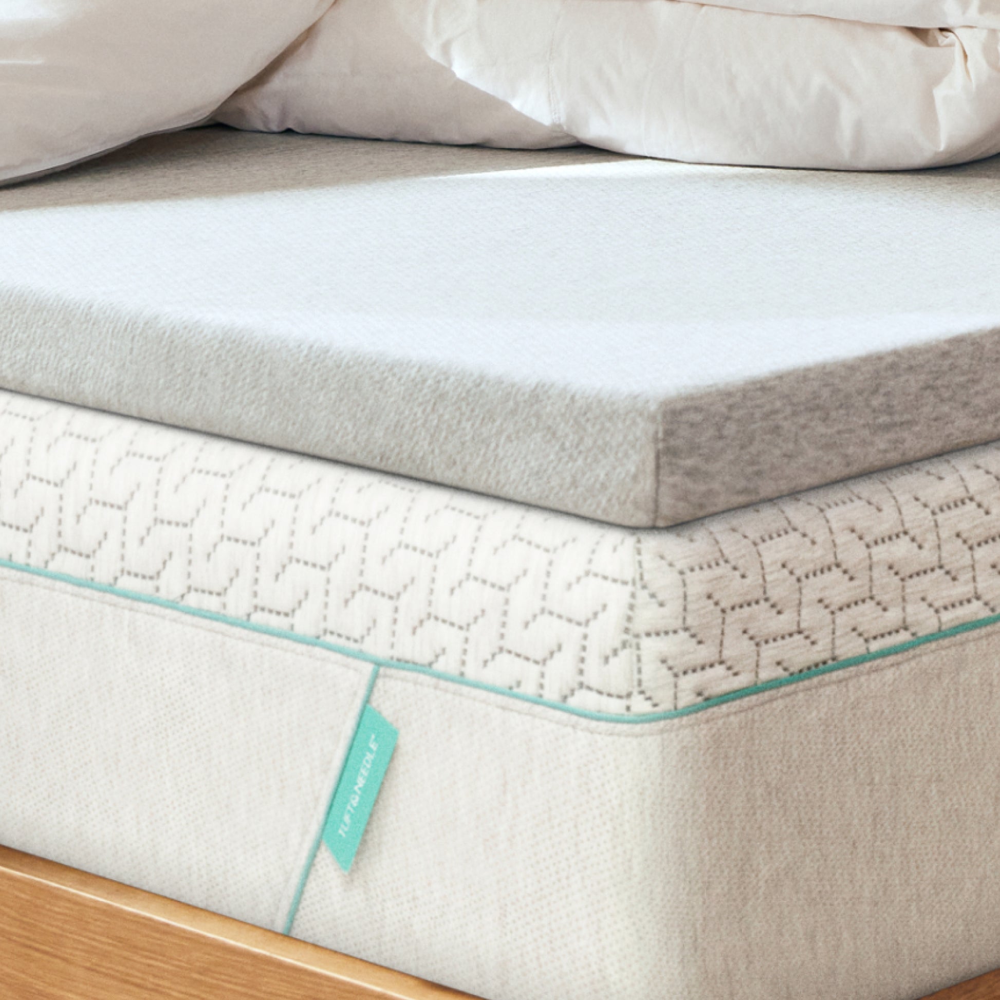 Tuft and Needle mattress topper on top of a Tuft and Needle Original mattress on wooden frame.