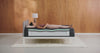 Woman rolls on to her side on a mattress that shows the inside layers to display pressure relief. 